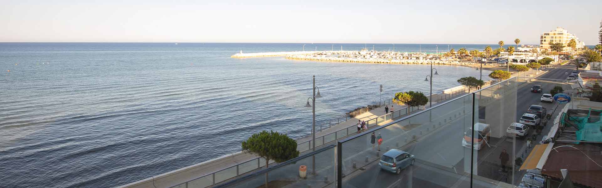 the view from the balcony of property showing the street, the pavement, the sea and the sky.